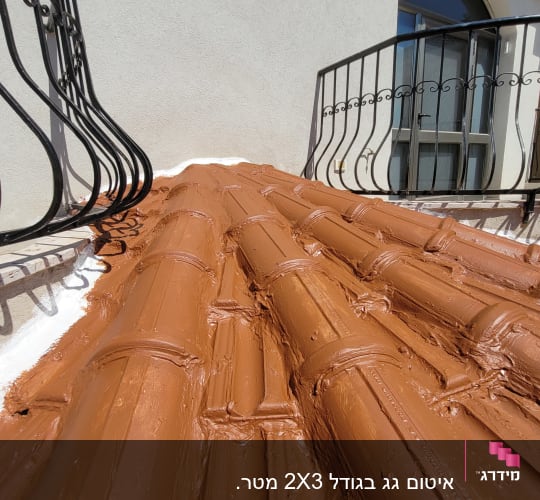רעפים חומים על גג עם מעקה ברזל שחור